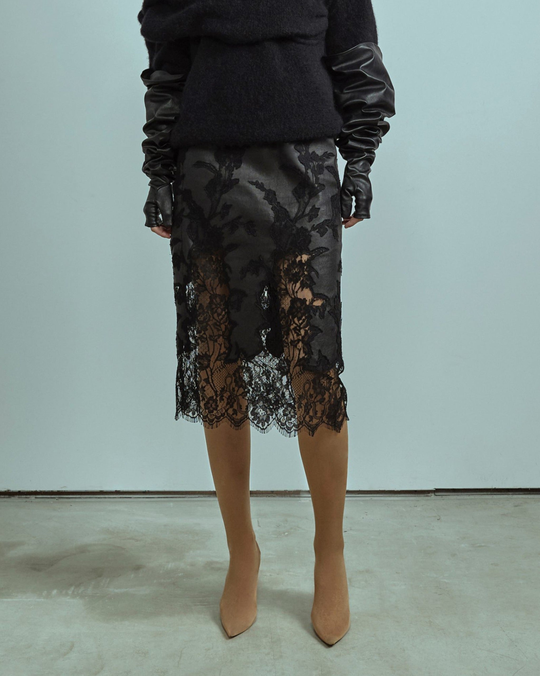 Person wearing a black lace skirt with a plain background made by ALMAZ