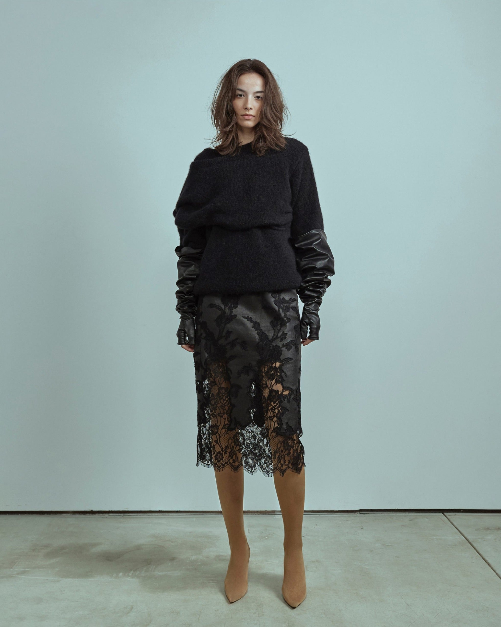 Woman wearing a black outfit with a lace skirt against a light blue background made by ALMAZ